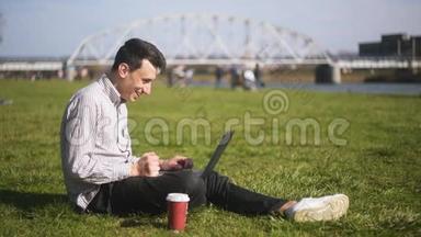 男孩检查笔记本电脑并收到好消息。 一个人坐在公园里，一个人刚刚赢得了一个大奖，终于发生了